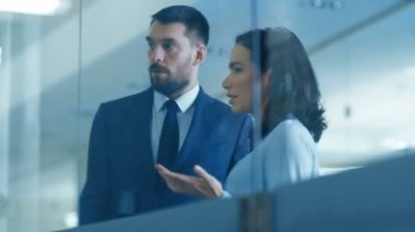 Üst Yöneticisi ve kadın Executive tartışmak dönemin şirket Modern cam ve beton Office ayakta iken en iyi duruma getirme planı.