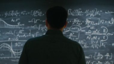 Parlak genç akademik yaklaşımlar Blackboard, karmaşık matematiksel formülü yazılı ile başlar çözüm hakkında düşünme.