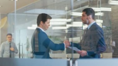 Kurumsal yapı koridorda el sıkışan iki iş adamları, onlar belgeleri karşılaştırmak. Manybusy iş arkadaşlarınızla meşgul ofis yaşam.