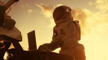 Astronot laptop, bir yeni yabancı gezegende kırmızı, ayarlama Rover uzay giysisi eserlerinde muhtemelen Mars. Gün ışık yüksek teknolojili uzay araştırmaları, keşfetmek ve yaşanabilir gezegenleri kolonize görev,.