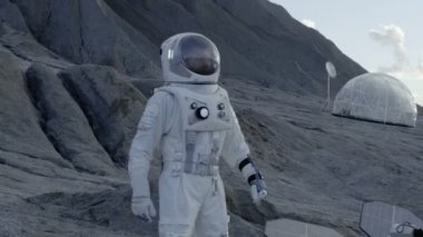 Astronot arıyor yabancı gezegende standları kollar Akimbo ile ayakta iken çevresinde. Onun Bankası arka planda / araştırma istasyonu. Uzay araştırmaları, kolonizasyon tema.
