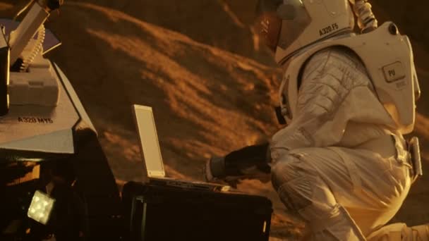 太空服上的航天员在笔记本电脑上工作 在新的外星人红色星球上调整漫游者 大概是火星 日轻高技术空间探索 发现和殖民宜居行星 — 图库视频影像