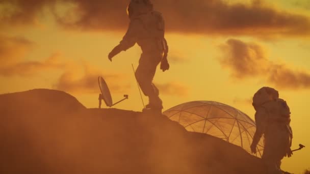 Два Силуэта Астронавтов Исследуют Планету Красных Скал Background Sunset Base — стоковое видео