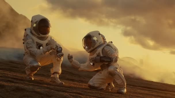 つの宇宙飛行士は 手のコンピューターで分析するエイリアンの惑星の土壌サンプルを収集します 火星火星有人探検隊 — ストック動画