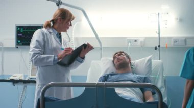 Hastanede profesyonel erkek doktor hasta ve tıbbi grafikte yazıyor cevaplar sorular sorar. Temiz ve Modern tıbbi Ward.