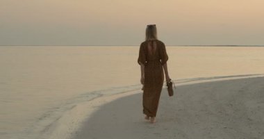 Aşağıdaki Shot sahilde yürüyüş bir içinde güzel kadın. Sakin deniz ve geç akşam renkler yumuşak sabah erken.