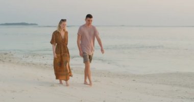 Güzel kadın ve yakışıklı adam sahilde yürüyor. Çift romantik gün harcama. Sakin, yumuşak erken sabah renkler sakin doğal doğa ve deniz gibi.