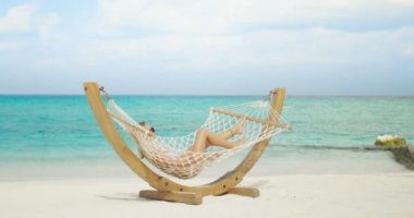 Pastoral sahne. Yalancı hamak bir plajda güneşlenirken güzel kadın. Azure plaj beyaz kum ve masmavi su ile. Güneş parlar egzotik yere.