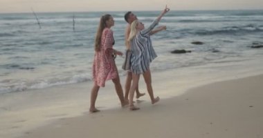 İki güzel kadınlar ve yakışıklı Fit sahilde yürümek, konuşmak ve eğleniyor dostum. Muhteşem doğal deniz içinde belgili tanımlık geçmiş.