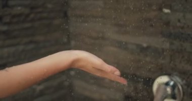 Duşta kadın su akışı altında elini yerleştirir. Onun avuç içinde iniş damlacıkları.