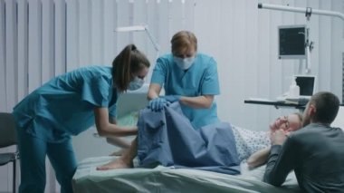 Emek vermek Doğum, bebek çıkıyor, Obstetricians teslim yardımcı olmak, eş tutan destekler karısı iter içinde hastane kadında. Yan görünümü görüntüleri.