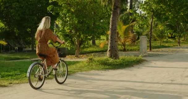 美しい女性のドレスを着て本物の村を通って道路に自転車に乗る 南アジアの自然 シーニックの森の道に成長 — ストック動画