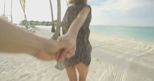 POV záběry. Krásná žena, drželi se za ruce s přítelem a běží směrem k moři. Bílý písek, palmy a zelené vody. Romantická dovolená ostrov Paradise.