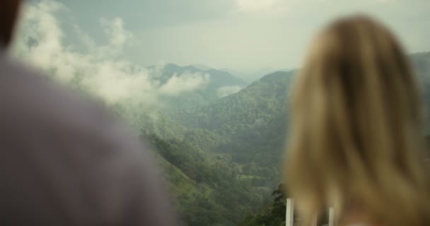 后面的景色年轻夫妇看着华丽的山山庄覆盖在森林 旅行的人和美丽的自然 — 图库视频影像