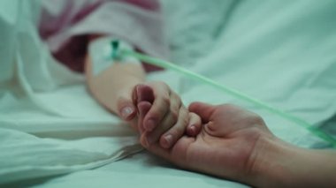 Kurtarma küçük çocuk elini rahatlatıcı uyku, Anne tutan hastane yatağında yalan. Ellerini üstüne odaklanmak. Duygusal aile an.