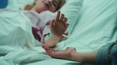 Küçük çocuk yalan hastane yatak uyku kurtarma, elini annemin düşer ve o Comfortingly tutar. Ellerini üstüne odaklanmak. Duygusal aile an.