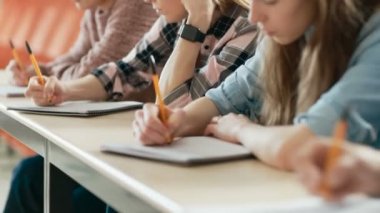 Görüntüleri bir satır çok etnik öğrencilerin sınava sınıfta hareketli / test Focus Holding kalem ve yazılı olarak dizüstü bilgisayarlar üzerinde. Üniversitesi'nde çalışma parlak gençler.