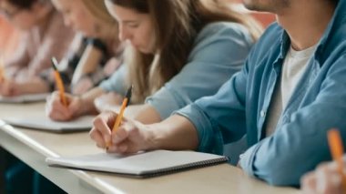 Görüntüleri bir satır çok etnik öğrencilerin sınava sınıfta hareketli / test Focus Holding kalem ve yazılı olarak dizüstü bilgisayarlar üzerinde. Üniversitesi'nde çalışma parlak gençler.