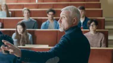 Kamera bakan Sınıfı: tahtaya yazma ve bir sınıfa ders veren ünlü Profesör çok etnik öğrenciler dolu. Modern Üniversitesi Konferans salonunda parlak genç ile.