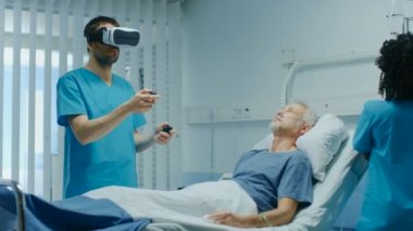 Doktor giyen sanal gerçeklik kulaklık ve Holding oyun çubukları tedaviler kıdemli yatakta yatan hasta. Fütüristik hastane koğuşunda kullanılan en gelişmiş teknolojiler.