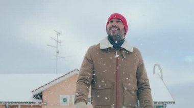 Portre Of yakışıklı adam yürüme onun arka bahçesinde bir güzel kış gününde. Yumuşak kar düşüyor.