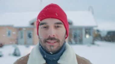 Portre Of yakışıklı adam yürüme onun arka bahçesinde bir güzel kış gününde. Yumuşak kar düşüyor.