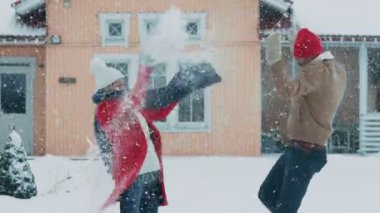 Genç çift şakacı hava, kar kış kar yağışı devam ederken atar. Mutlu adam ve kadın kar pastoral evlerinin bahçesinde oynarken. Aile kış keyfi.
