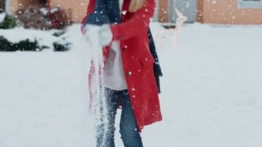 Mutlu genç gülen kadın kar havaya atar. Kış günü evinin arka bahçesinde kız bir eşarp ile kırmızı paltolu hoşlanır.