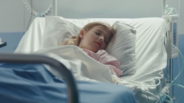 可爱的小女孩睡在儿童医院的一张床上 关心母亲用毯子和爱抚覆盖她的前头 具有高素质保健的现代儿科病房 — 图库视频影像