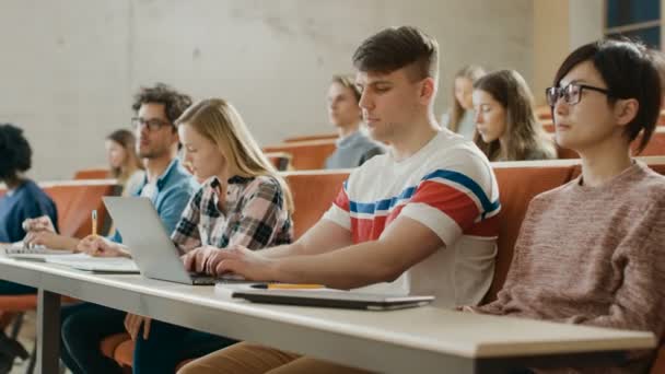 英俊的白种人学生在大学听讲座时使用笔记本电脑 现代光明学生的多民族对他们的未来所感兴趣 — 图库视频影像