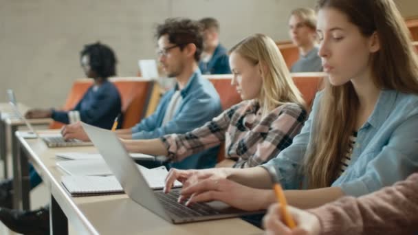 在多民族学生的课堂上 在听讲师讲课时使用笔记本电脑 有的写在笔记本上 明亮的年轻人在大学学习 — 图库视频影像