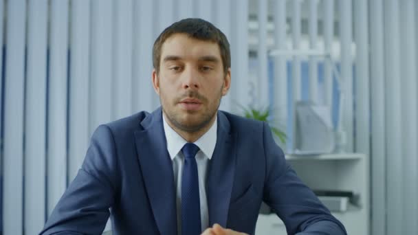 Schöner Seriöser Geschäftsmann Sitzt Seinem Schreibtisch Spricht Die Kamera Gestikuliert — Stockvideo