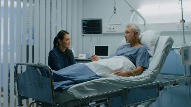 在医院里 病房里的父亲是由女儿访问的 老年病夫躺在床上与长大的女儿会谈 现代私人病房 — 图库视频影像