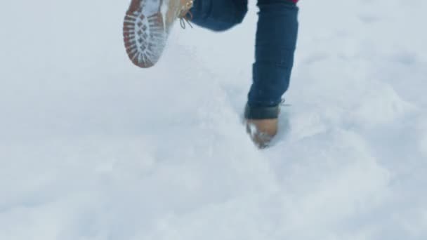 次の雪の上を実行している女性の映像 足に焦点を当てます 新鮮な雪と美しい白い冬の天候 女性が雪の中に足跡を残す — ストック動画
