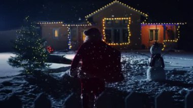 Noel Baba kırmızı çantalı görüntülerini düşük açılı ışıklar ve çelenk ile dekore edilmiş olan pastoral evin ön bahçesine içine yürüyor. Santa hediyeler ve Presents gece getiriyor. Büyülü New Year's Eve düşen kar.