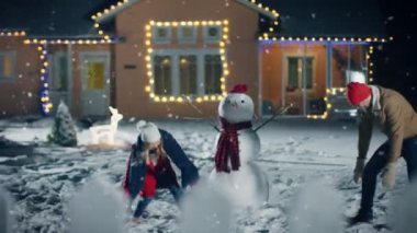 Genç güzel çift atar kartopu birbirlerine ise kar düşüyor. Mutlu adam ve kadın onların pastoral evi dekore edilmiş Noel arifesi için açık avlu karda oynarken. Beyaz Noel akşam zevk aile.