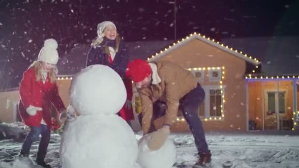 Χαρούμενος Νέοι Οικογένεια Κάνοντας Χιονάνθρωπος Στην Πίσω Αυλή Του Σπιτιού — Αρχείο Βίντεο
