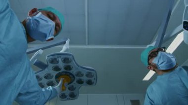 Düşük Açı Atışı Hasta Görüşü: İki Profesyonel Cerrah Hasta Eğilirken Ameliyat Işıklarını Açtı.