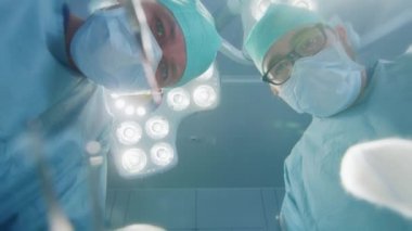 Düşük Açı Atışı Hasta Görüşü: Ameliyata Başlayan İki Profesyonel Cerrah Cerrahi Aletleri Tutuyor.