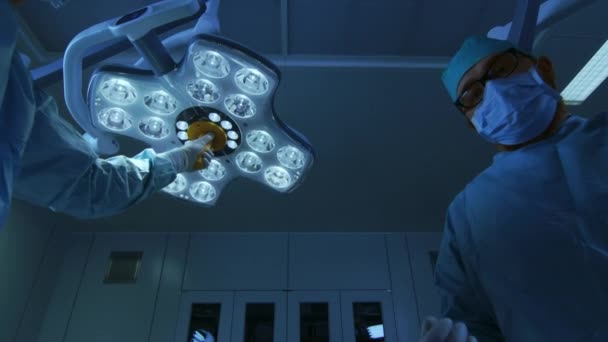 Χαμηλή γωνία shot κοιμάται POV ασθενή θέα: δύο επαγγελματίες χειρούργοι ενεργοποίηση φώτα χειρουργική ενώ αναισθησιολόγος βάζει αναισθησία μάσκα. — Αρχείο Βίντεο