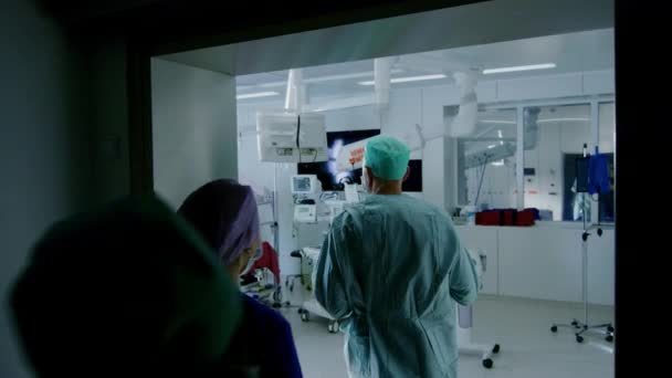 Na een shot van divers team van chirurgen en assistenten lopen in de operatiekamer waar de patiënt wacht, ze zetten hem onder anesthesie en start chirurgie. Echt modern ziekenhuis met authentieke uitrusting. — Stockvideo