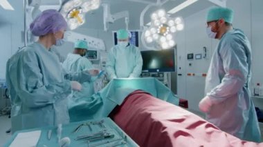 Hastane Ameliyathanesinde Bir Hastaya İnvaziv Cerrahi Yapan Çeşitli Profesyonel Cerrahlar Ekibi. Hemşire Bir Baş Cerrah için Enstrüman Passes, Anestezist Monitörler Vitals. Tam Fonksiyonel Gerçek Ekipman.