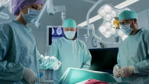 Diverse Team of Professional Surgeons Performing Invasive Surgery on a Patient in the Hospital Operating Room. L'infirmière passe l'instrument à un chirurgien en chef, l'anesthésiste surveille les signes vitaux. Équipement réel entièrement fonctionnel . — Video