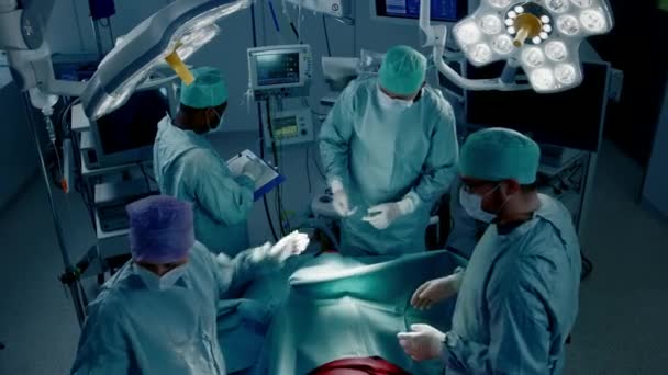 High Angle Shot of Diverse Team of Professional surgeon,  Assistants and Nurses Performing Invasive Surgery on a Patient in the Hospital Operating Room. Real Modern Hospital with Authentic Equipment. — Stock Video