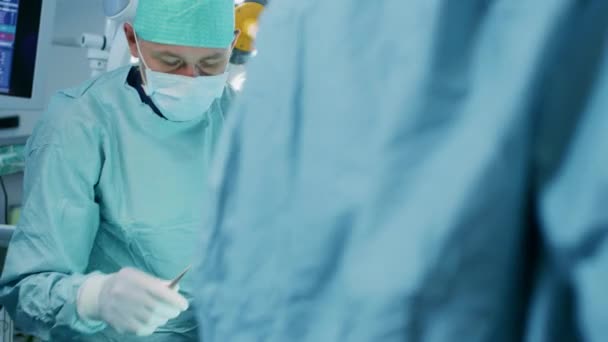 Närbild skott i operationssalen, assistent händer ut instrument till kirurger under drift. Kirurger utför drift. Professionella läkare som utför kirurgi. — Stockvideo