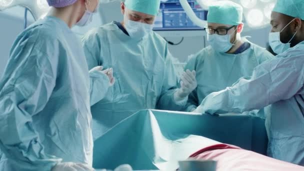 専門医、アシスタント、看護師の多様なチームが、病院の手術室で患者に侵襲手術を行います。本物の機器を備えた本物の近代病院. — ストック動画