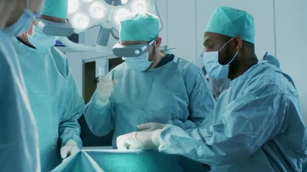 Chirurgen dragen Augmented Reality Glasses Voer State of the Art Mixed Reality Surgery uit in het High Tech ziekenhuis. Artsen en assistenten werkzaam in de operatiekamer. — Stockvideo