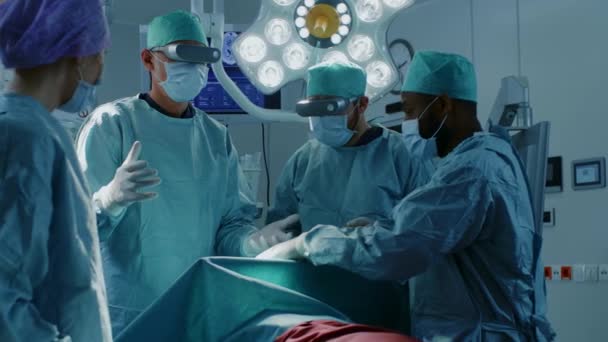Chirurgen setzen eine Augmented-Reality-Brille auf, um im High-Tech-Krankenhaus hochmoderne Operationen durchzuführen. Ärzte und Assistenten arbeiten im Operationssaal. — Stockvideo