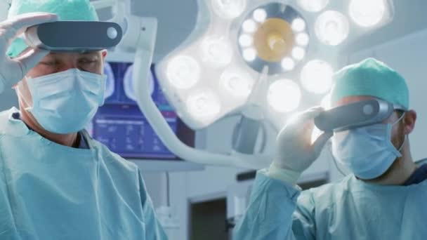 Chirurgen zetten Augmented Reality Glasses op om state of the art chirurgie uit te voeren in het High Tech ziekenhuis. Artsen en assistenten werkzaam in de operatiekamer. — Stockvideo