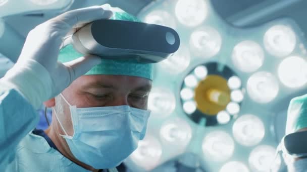Primer plano de un cirujano que se pone gafas de realidad aumentada para realizar una cirugía de última generación en el hospital de alta tecnología. Médicos y asistentes que trabajan en quirófano . — Vídeos de Stock